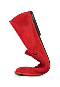 Roter Wildleder-Slipper, der gebogen ist, um seine flexible Sohle und das weiche Material vor einem weißen Hintergrund zu zeigen.