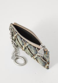 Denim coin pouch with a zippered opening, silver hardware, and chain attachment. Features light and dark blue fabric sections with stitches.