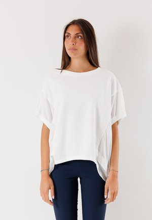 Top bianco a maniche corte con una vestibilità rilassata, design a strati e scollatura rotonda. Abbinato a pantaloni aderenti blu scuro. Tessuto liscio.