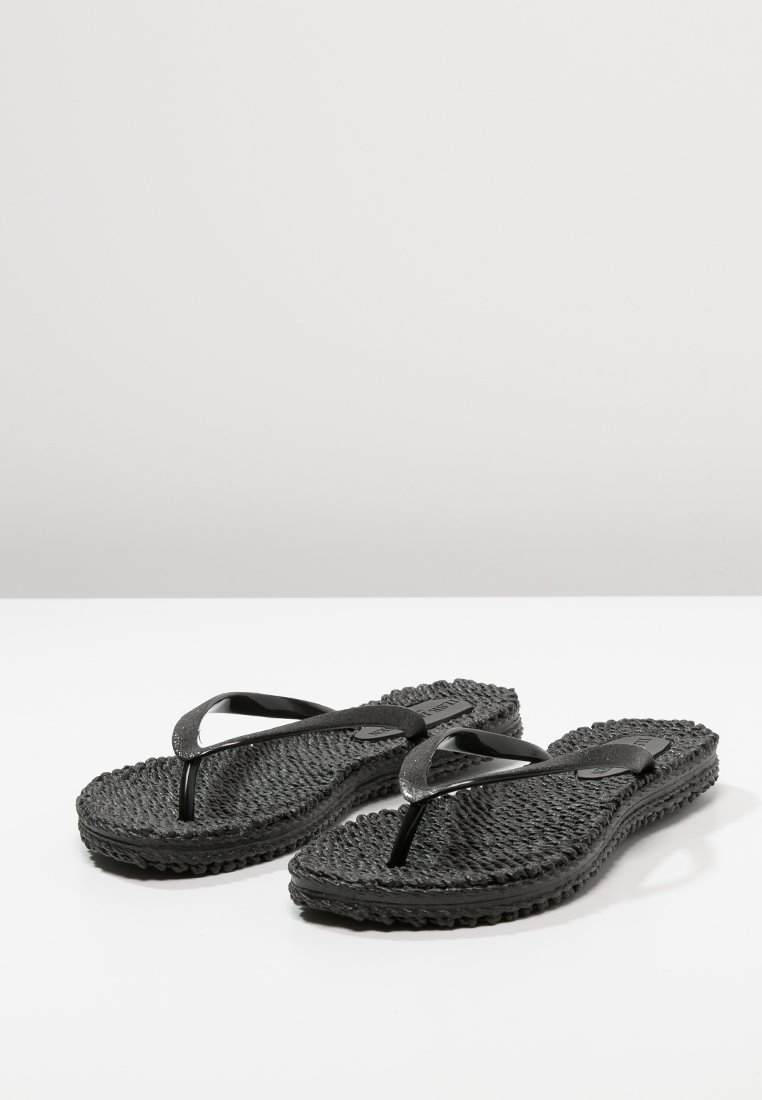 Paar schwarze, strukturierte Flip-Flop-Sandalen mit einfachen Y-förmigen Riemen auf einer schlichten weißen Oberfläche.