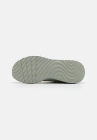 Suela de zapato con un patrón ondulado, hecha de un material verde claro y suave; presenta ranuras para tracción y una punta redondeada.
