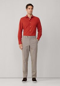 Rotes Hemd mit Knopfleiste, hellgraue karierten Hosen und dunkelbraune Sneakers. Slim Fit Design mit glatter Textur. Lässiges Ensemble.