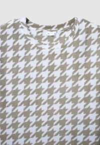 Sweatshirt léger, beige et blanc à motif pied-de-poule, avec un col rond et un tissu doux et texturé. Étiquette visible à l'intérieur du col.