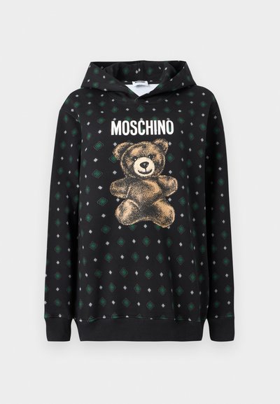 Μαύρο φούτερ με γραφικό στοιχείο αρκουδάκι σε χρυσό, η λέξη "Moschino" επάνω και ένα μοτίβο από πράσινα διαμάντια και γκρι σχήματα σε όλο το ύφασμα.