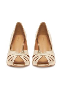 Kuldne metallik kõrged kontsad avatud varbaga disainiga, millel on ees risti rihmade detail. Sile viimistlus ja terava näpuga kuju.