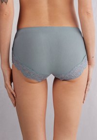 Lichtblauwe onderbroek van een gladde stof, met een golvende lavendelkleurige kantafwerking aan de randen. Eenvoudig ontwerp, zonder patronen of versieringen.