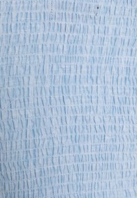 Tessuto azzurro chiaro con una texture smockata, caratterizzato da righe orizzontali di cuciture arricciate e un aspetto morbido e arioso.