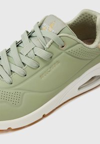 Svijetlozelene tenisice s gumenom potplatom, perforiranim dizajnom, podstavljenim ovratnikom i odgovarajućim vezicama. "Skechers" logo u zlatnoj boji na jeziku.