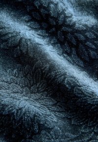 Material de catifea de culoare albastru închis, cu un model texturat floral, având un luciu subtil și o suprafață moale, plină.