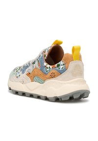 Zapatilla multicolor con patrones florales, suela gris, materiales de ante y malla, acentos texturizados y una lengüeta amarilla en el talón.