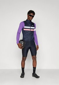 Dviračių apranga, kurioje tamsiai mėlyna liemenė su baltais, rožiniais ir violetiniais dryžiais, violetinės ilgomis rankovėmis, juodi šortai ir juoda šalmas.