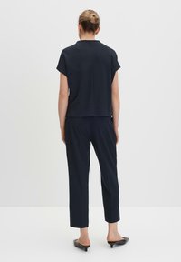 Navyblauwe top met korte mouwen en een rechte snit, gecombineerd met bijpassende tapered broek. Glad materiaal met een eenvoudig ontwerp en minimale details.