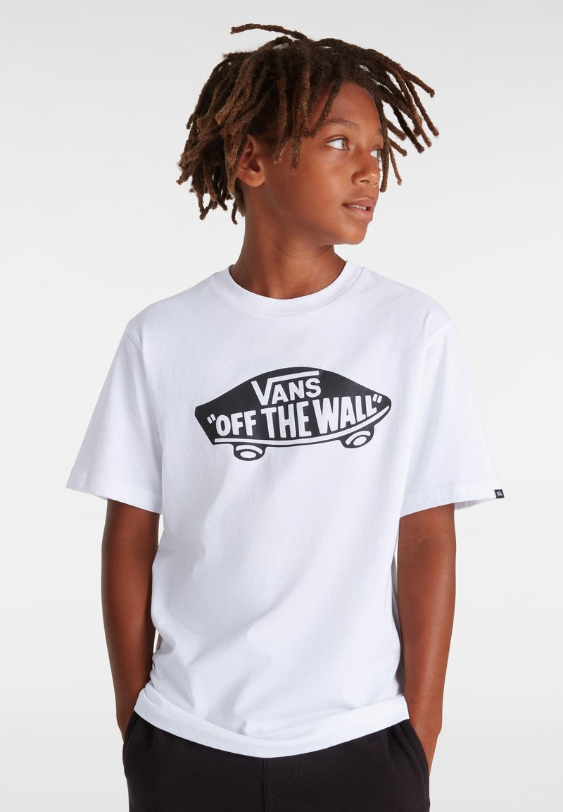 Camiseta de algodón blanca con un gráfico negro "VANS 'OFF THE WALL'" en el centro. Diseño de mangas cortas y cuello redondo.