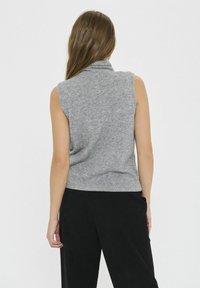 Top gri fără mâneci, cu guler înalt, fabricat dintr-un material tricotat moale. Prezintă un design ajustat și o terminare cu nervuri. Pantaloni negri vizibili.