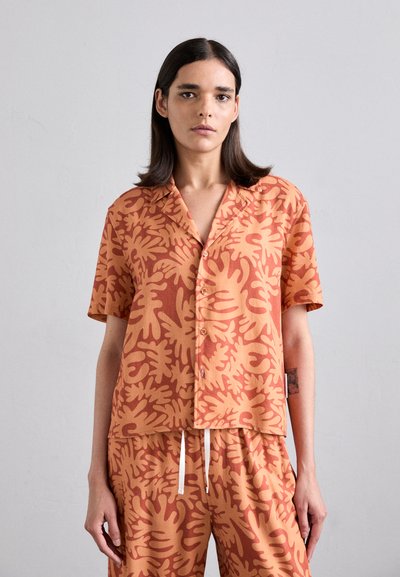 Short-sleeve shirt in a rust color with a botanical pattern. Made from soft fabric, featuring a button-up front and collar.