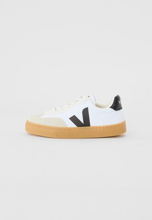 Valge kanvasest sneaker, millel on beežist nahast varvaste kaitse, must logo ja kummist tallad. Omab lamedaid kingapaelu ja pehmendatud krae.