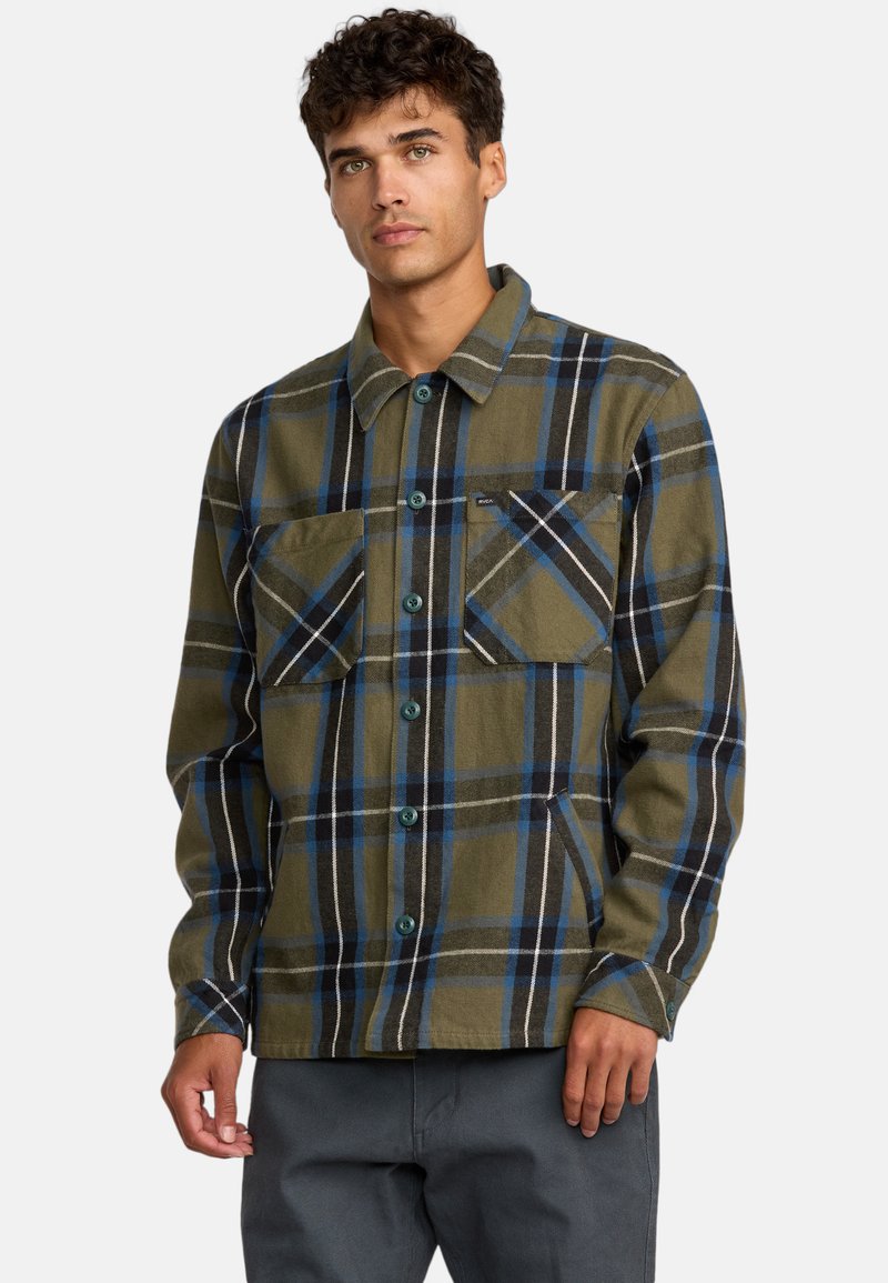 Camicia in flanella a quadri verdi e blu navy con chiusura a bottoni, due tasche sul petto e bottoni in plastica. Tessuto morbido e vestibilità casual.