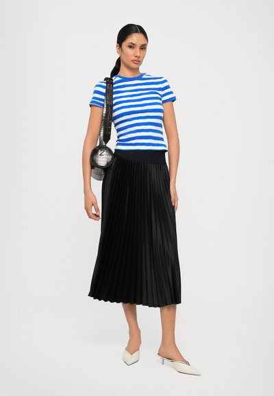 Striped blue and white short-sleeve top paired with a flowy black pleated skirt. The outfit includes a textured black circular bag and white mules.