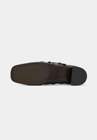 Shoe sole in black rubber with a flat profile. Features a smooth texture and a rounded heel, visible stitching along the sides for detail.