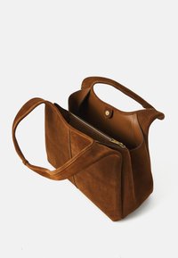 Bruine suède handtas met twee handvatten aan de bovenkant, een ritsvak aan de binnenkant en een gladde binnenkant. Heeft een geometrisch ontwerp en een metalen drukknoopsluiting.