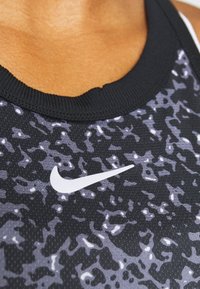 Canottiera sportiva a righe nera e grigia con scollatura a coste, arricchita con il logo Nike bianco sul davanti. Tessuto elasticizzato.