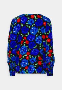 Blouse noire à manches longues, ornée de grands motifs de fleurs bleues et de petites fleurs rouges avec des feuilles vertes.