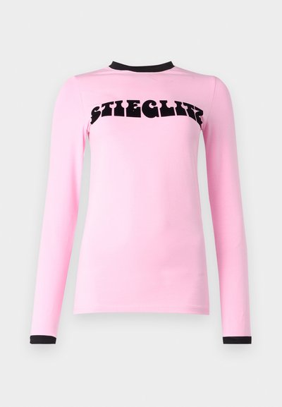 Long-sleeve pink shirt featuring a rounded neckline with black trim and bold black text reading "SHEGLAM" across the chest. Smooth texture.