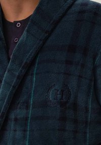 Męski szlafrok w ciemnozieloną kratę, wykonany z miękkiego materiału, z kołnierzem, zapięciem na guziki i haftowanym logo w okrągłym wzorze.