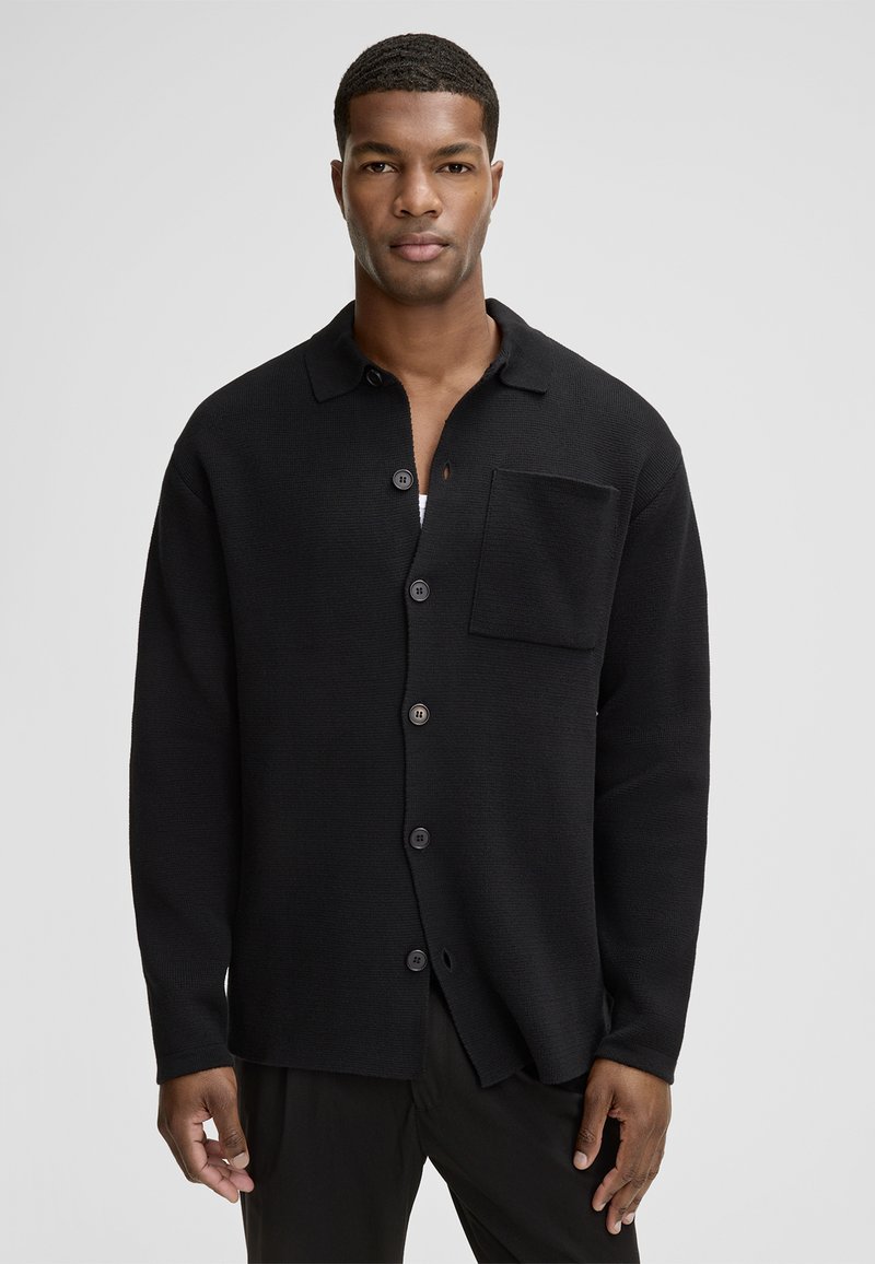 Czarny kardigan wykonany z teksturowanej tkaniny, z zapięciem na guziki z przodu, pojedynczą kieszonką na piersi oraz długimi rękawami w luźnym fasonie.