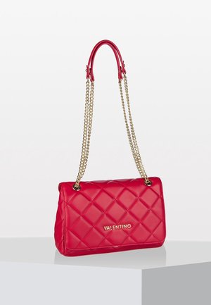 Rode gewatteerde Valentino-handtas met gouden kettingband en leren handvatten, rustend op een wit displayoppervlak.