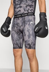 Luvas de boxe pretas; calções de compressão cinza camuflados com as marcas Venum e Polaris, apresentando um ajuste justo e textura suave.