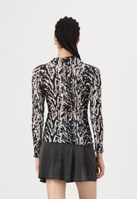 Long-sleeve top in black and white abstract pattern, featuring a high neckline and fitted silhouette, made of lightweight, textured fabric.