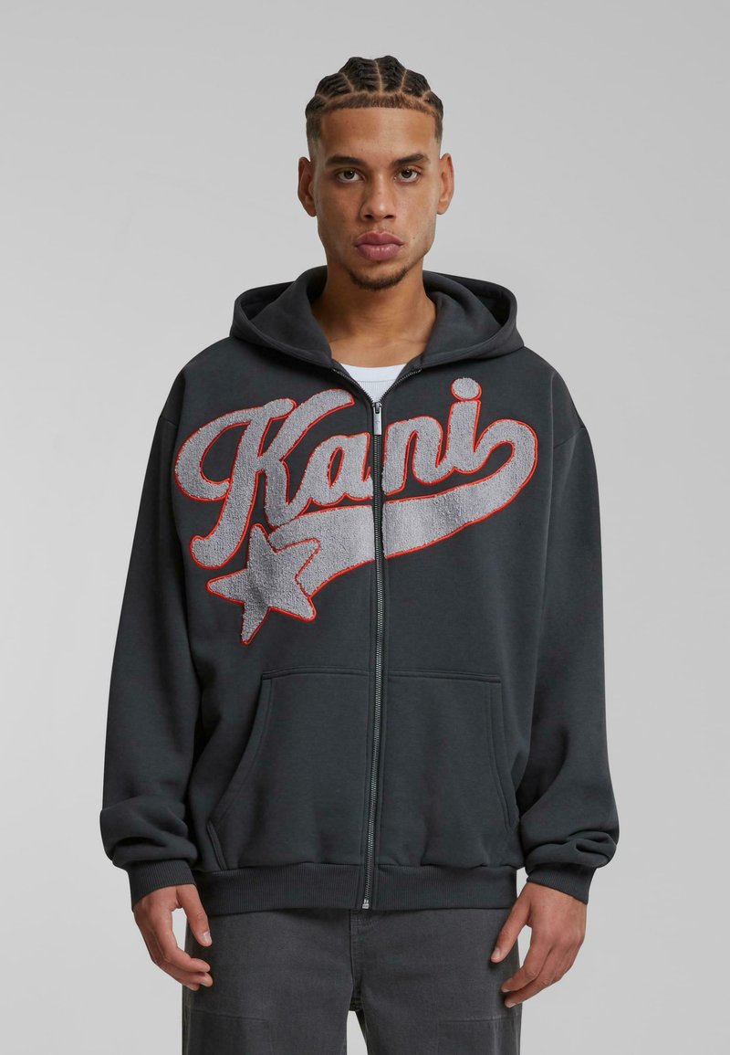 Sort zip-up hoodie med stort gråt og rødt broderet tekst "Kani" med en stjerneaccent, forlommer og snørredragt.