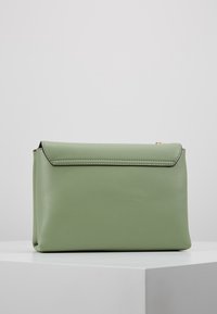 Borsa verde in finta pelle con design piatto, chiusura a ribalta e cuciture minime. Presenta una superficie liscia e nessun hardware visibile.