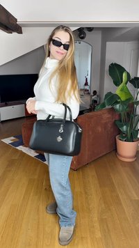 Must mustriga mustkott, millel on ümar kuju, lukuga sulgemine ja hõbedane südamekujuline kaelakee. Kandmiseks valge kudumitoote ja siniste teksadega.