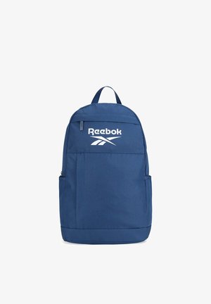 Mochila azul de Reebok con bolsillo delantero con cremallera, bolsillos laterales, asa superior y logotipo blanco de Reebok en la parte superior del panel frontal.