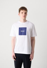 Bílý bavlněný tričko s čtvercovou námořnickou logem s nápisem "BARBOUR INTERNATIONAL" v bílé barvě. Krátké rukávy, kulatý výstřih.