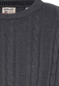 Grafitowy sweter z prążkowanym splotem, wzorem w warkocze oraz zaokrąglonym dekoltem. Widoczna metka z nazwą marki i logo.