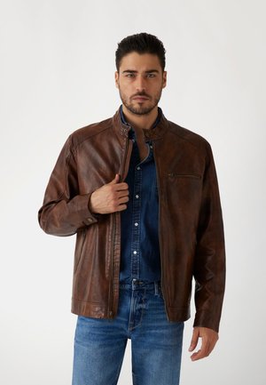 Brun läderjacka med dragkedja framtill och ställbar krage. Har en bröstficka och slät yta, kombinerad med en denimskjorta.