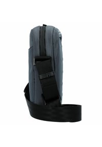 Borsa a tracolla grigia in tessuto con superficie testurizzata, una tracolla nera e una zip superiore. Presenta una forma rettangolare slanciata con tasche laterali.