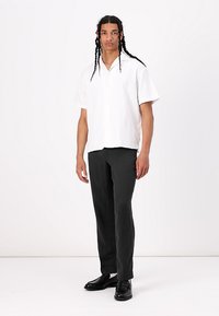 White short-sleeve shirt, black textured trousers, and black shoes. The shirt features a buttoned neckline, while trousers have a straight cut.