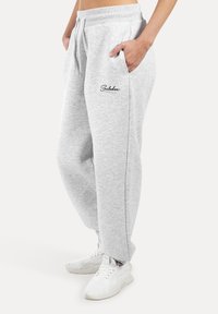 Helle graue Jogginghose aus weichem Baumwollmix, mit elastischem Bund, seitlichen Taschen und einem kleinen Logo am linken Oberschenkel.