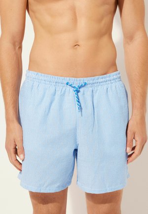 Hellblaue gestreifte Badeshorts mit elastischem Bund und Kordelzug. Hergestellt aus einem glatten Stoff, mit seitlichen Taschen.