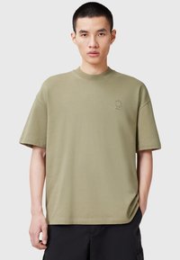T-shirt oversize verde olivo realizzato in cotone. Presenta un colletto rotondo, maniche corte e un piccolo logo sul petto. Texture liscia.