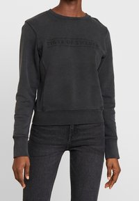 Felpa grigio scuro in misto cotone, con scollo tondo a coste, maniche lunghe e logo "TIGER OF SWEDEN" in rilievo sul petto.