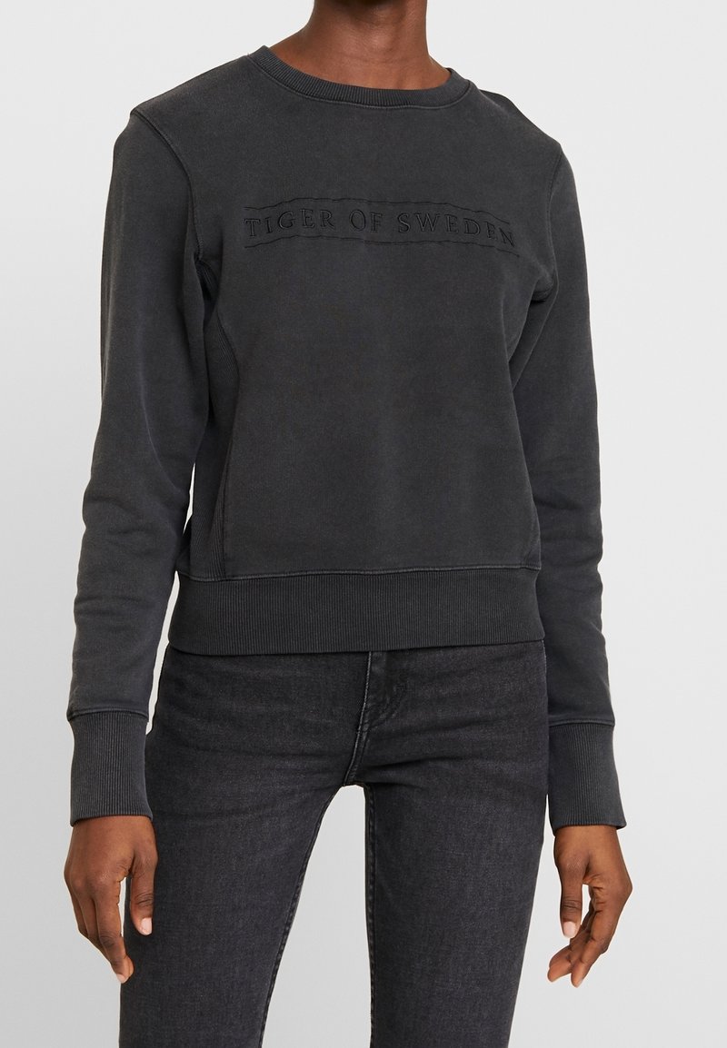 Felpa grigio scuro in misto cotone, con scollo tondo a coste, maniche lunghe e logo "TIGER OF SWEDEN" in rilievo sul petto.