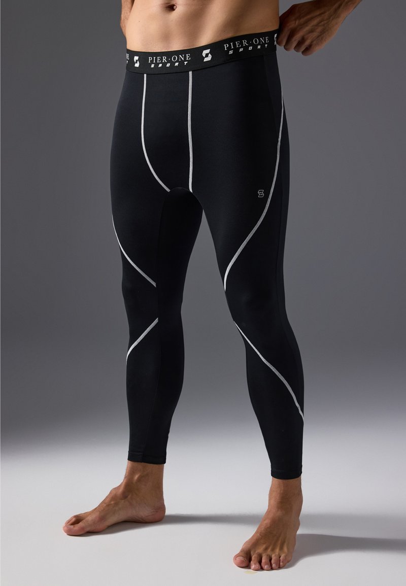 Black athletic leggings with silver accent stitching, a wide fitted waistband, and stretchable material for comfort and movement.