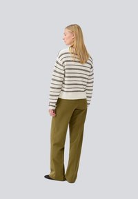 Maglione a righe in crema e marrone, abbinato a pantaloni larghi verde oliva. Tessuto morbido, design cropped e polsini e orlo a costine.