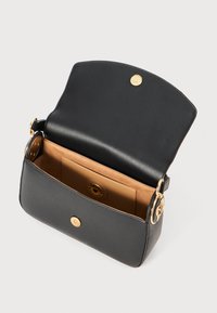 Schwarze Handtasche aus Kunstleder mit strukturierter Form, goldenen Beschlägen und einem magnetischen Druckknopfverschluss. Das Innere ist mit einem hellbraunen Futter versehen.