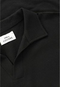 Sort bomulds polo-shirt med en klassisk krave, struktureret materiale og et lille vævet mærke med brandnavnet "CISZERE."
